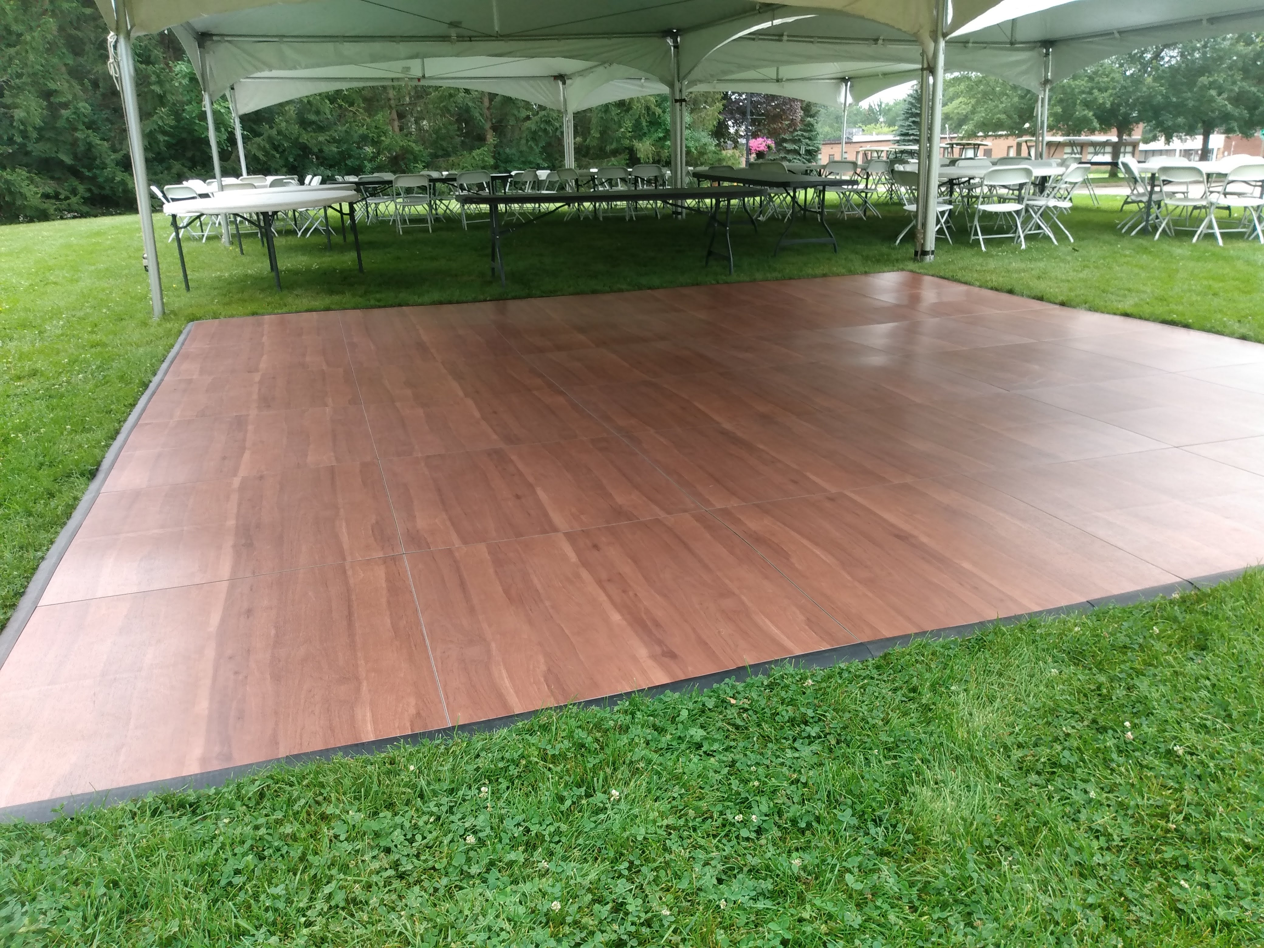 Dark Maple dance floor installed under frame tent, outdoor setup