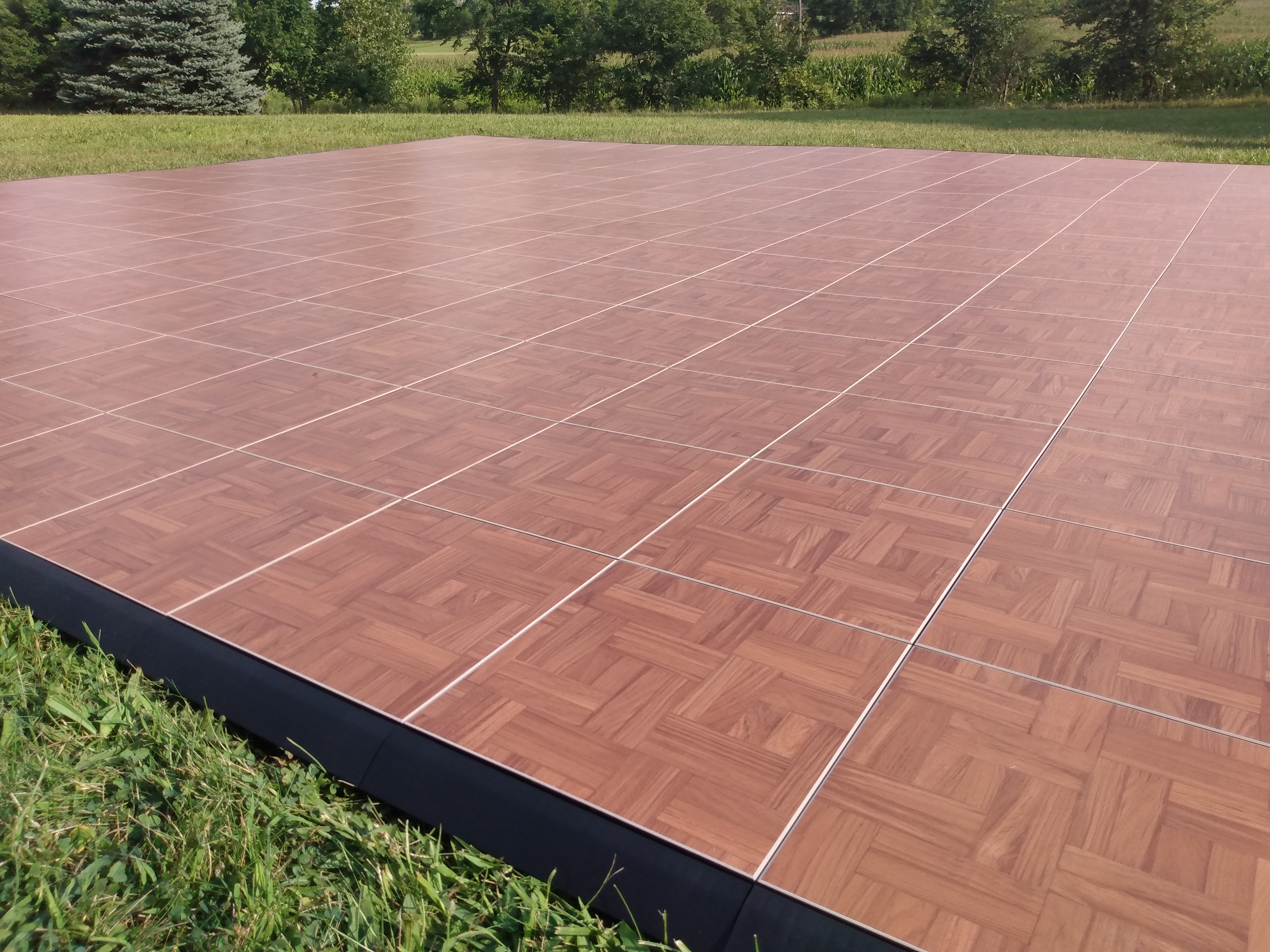 Large Dark Maple portable dance floor installed on grass
